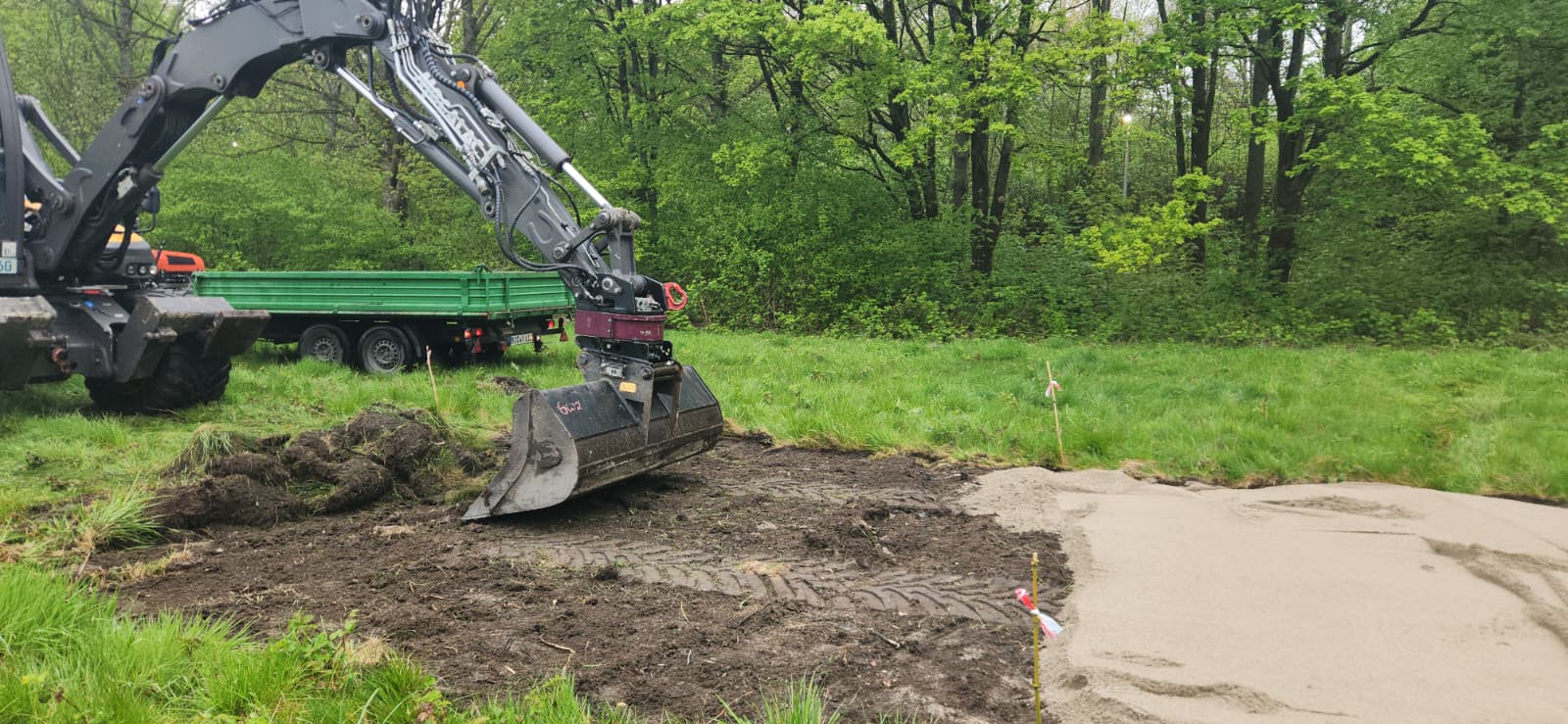 Ein Bagger entfernt die Grasnarbe.